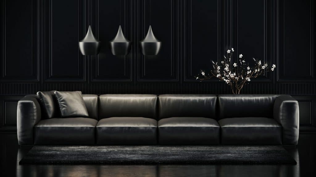 A dark color inspired living room with a long dark sofa, three black dangling lamps, and a dark painted wall