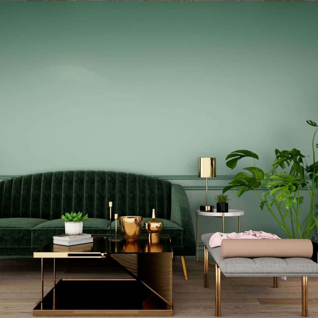 A green color themed living room with a green long sofa, golden figurines and furnitures, and a small indoor plant on the side
