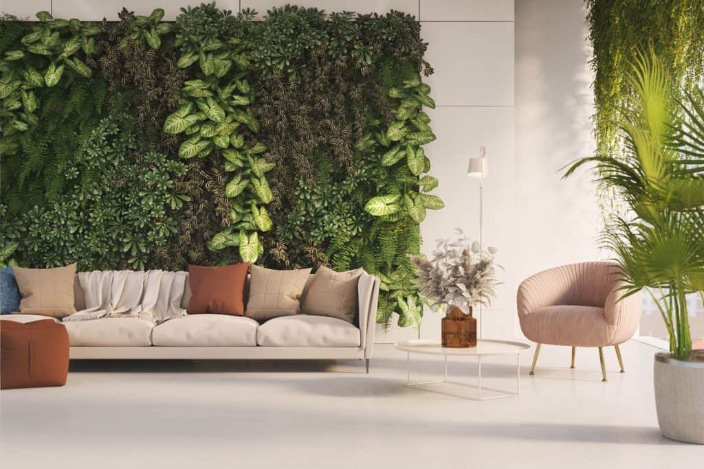 A green themed living room with an indoor vertical garden, cream colored sofa, and throw pillows
