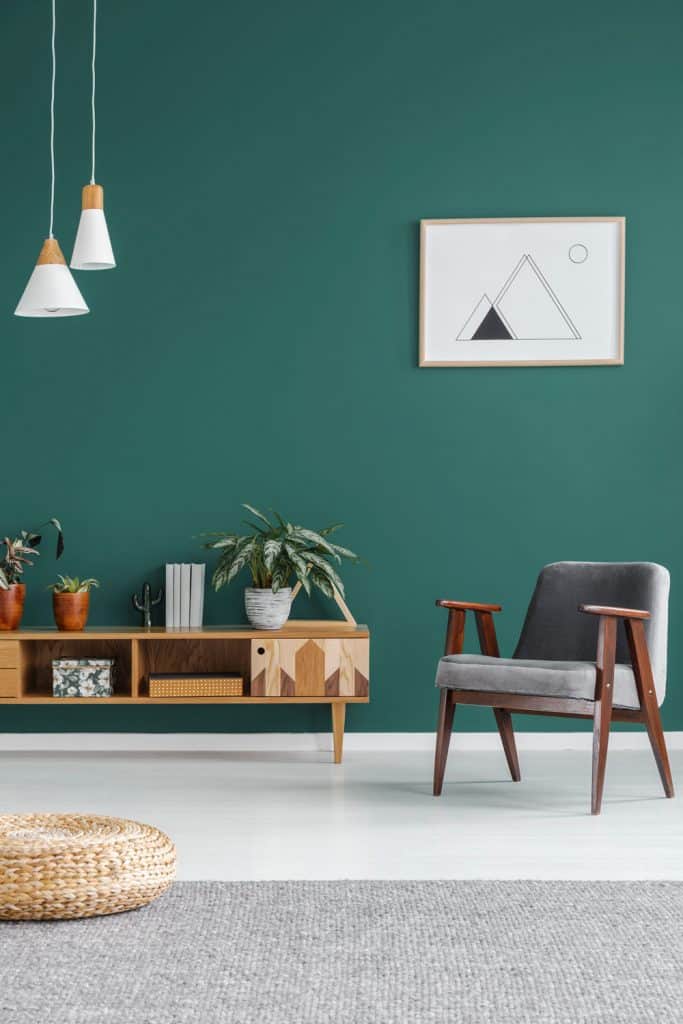 A green wall living room with a small wall unit on the background, a green chairs, and dangling lamps
