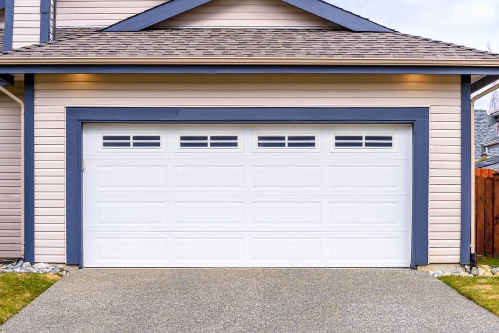 A huge white colored garage door with blue painted trims