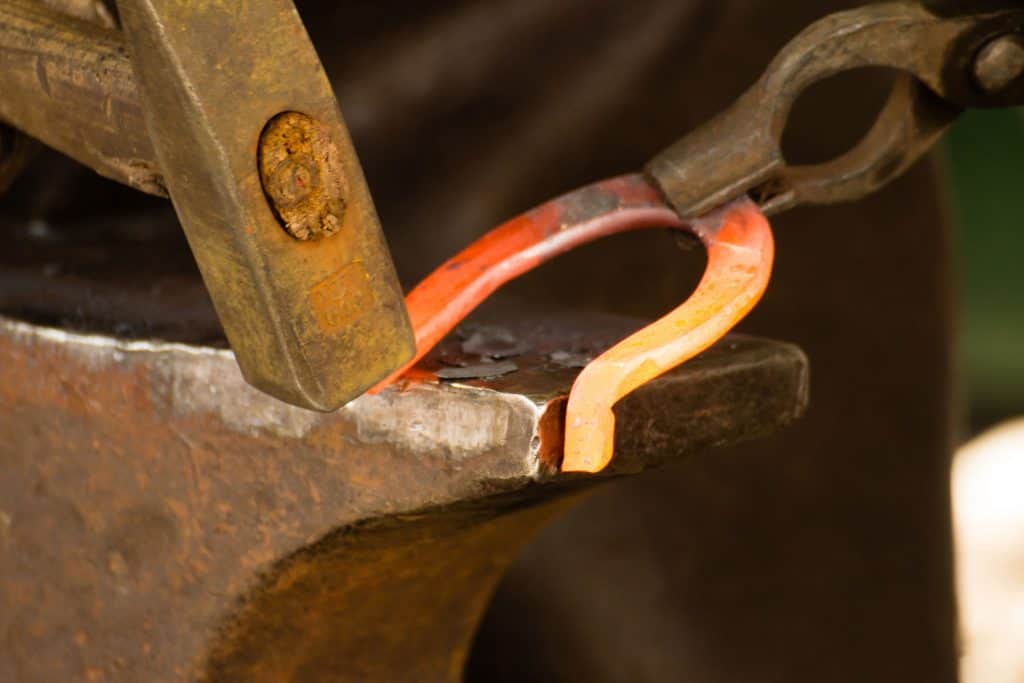 A man shaping a horseshoe using a hammer
