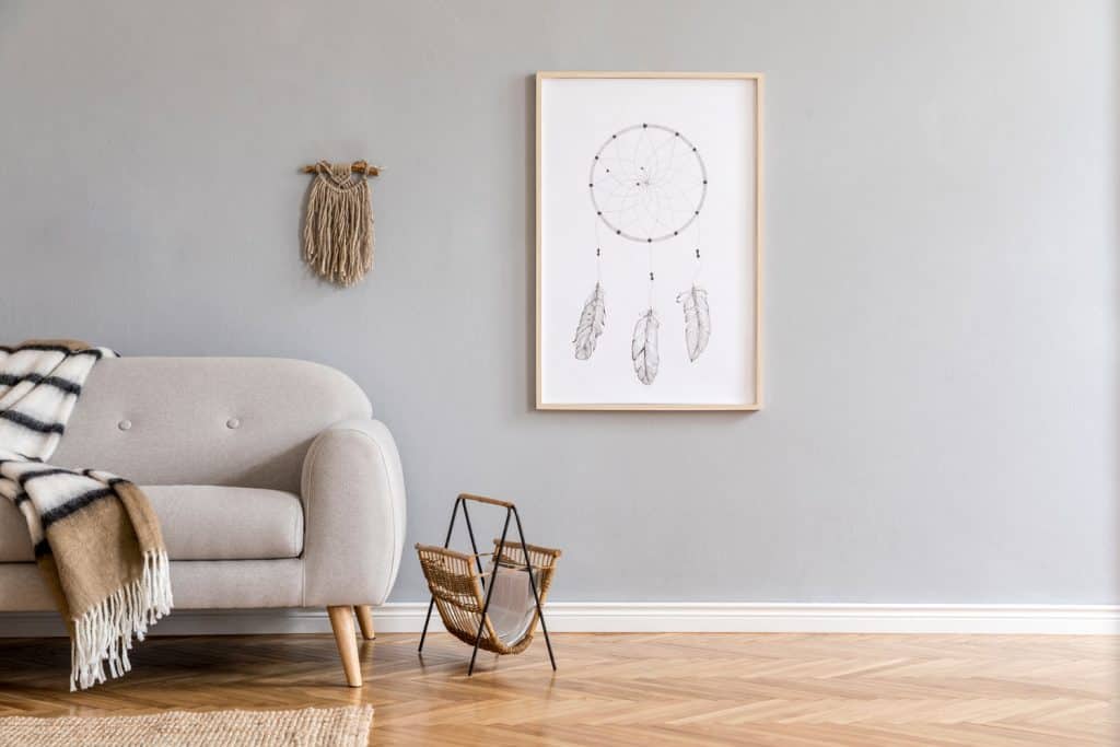 Un salon à thème minimaliste avec un mur peint en gris, un sol en bambou et un canapé-lit gris avec des rideaux