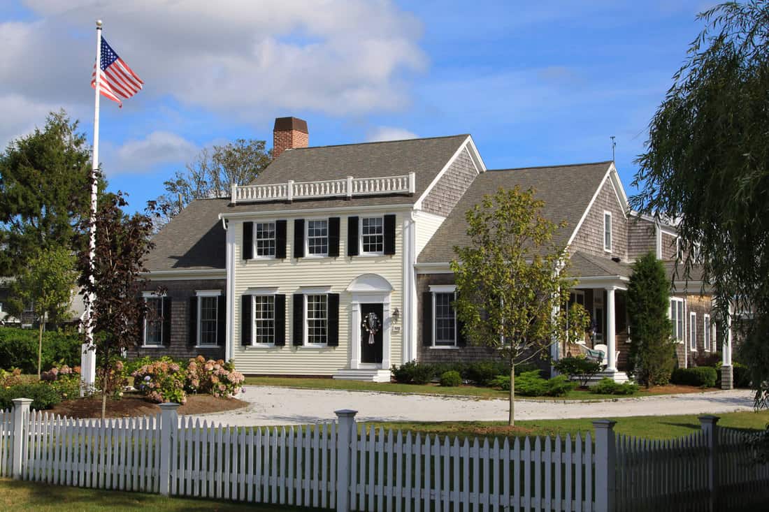 A modern American home with white painted sidings, black shutters, and weathered shingle roofing, 11 Stunning Houses With Black Shutters