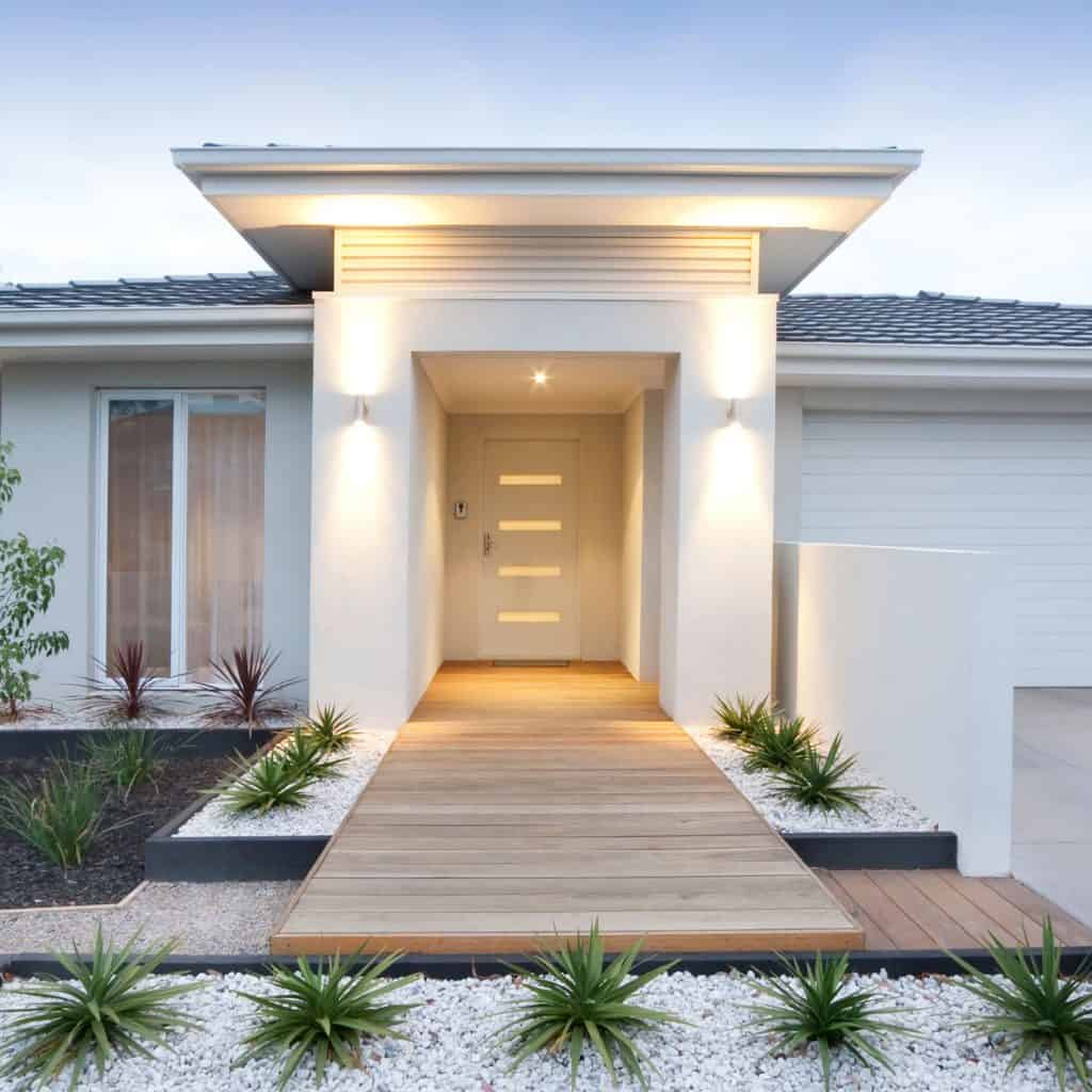 A modern contemporary front porch with a white front door with with panels and outdoor wall lamps
