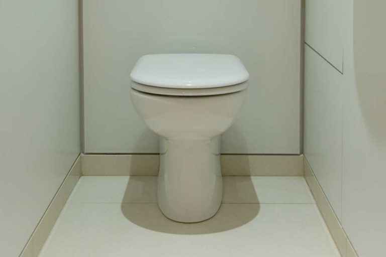 A modern toilet with tiled floor, opaque glass panels and hidden flush mechanism, How Much Space Do You Need For A Toilet?