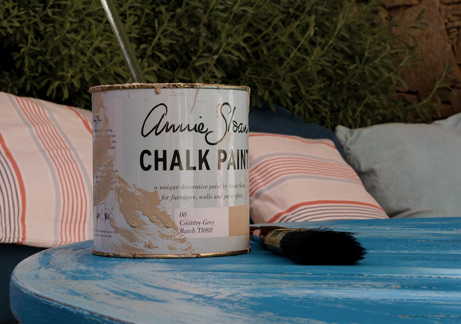 A tin of country grey Annie Sloan chalk paint on the vintage table next to the paintbrush