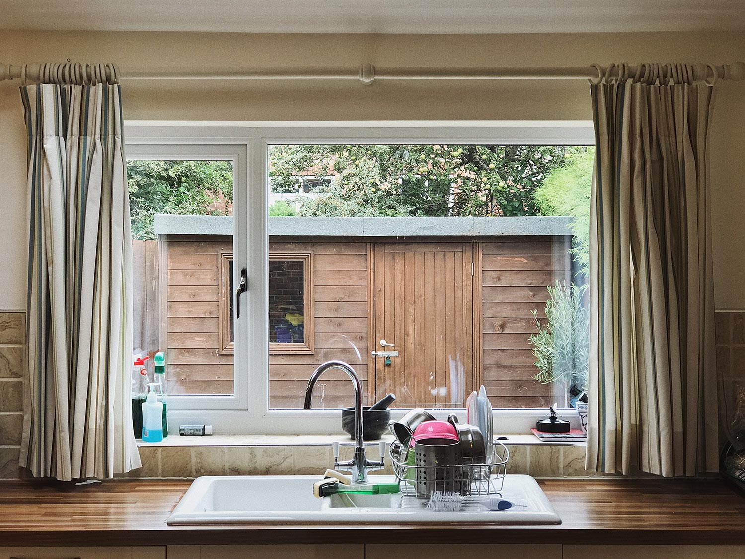 A view through an English kitchen window with dishes are washed and stacked