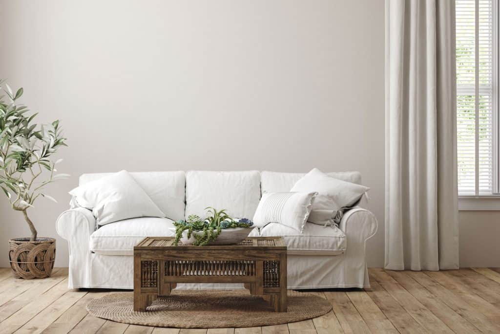 A white colored sofa with white throw pillows incorporating the themed of the living room and furnitures