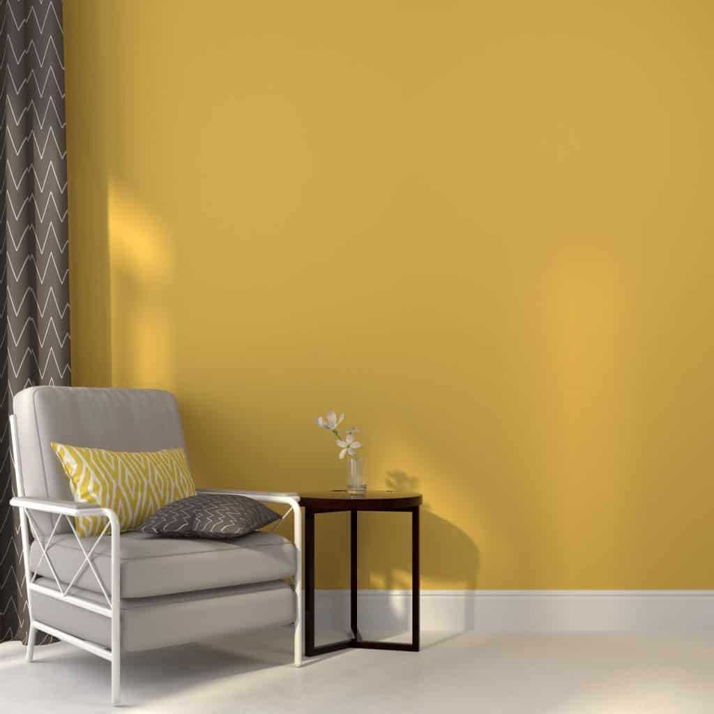 A yellow living room with a gray chair and an end table with a small plant on top