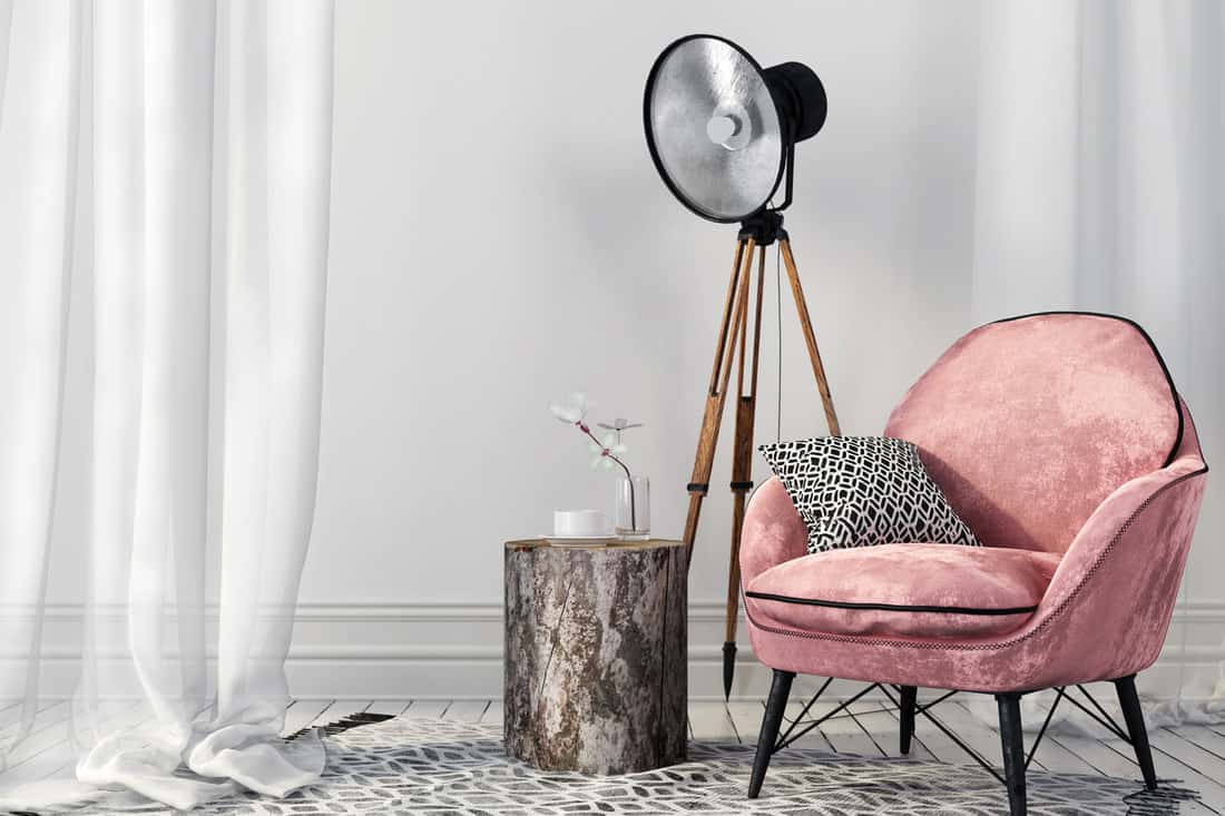 Air white interior with a stylish pink chair on metal legs and a vintage spotlight