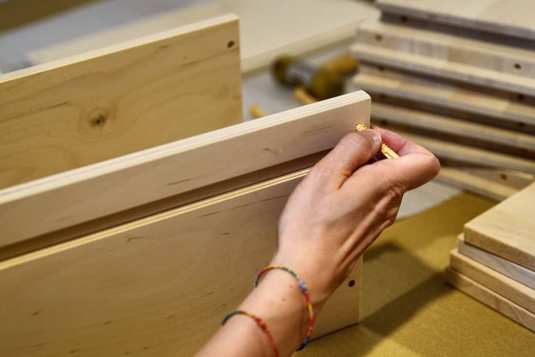 Assembly of an Ikea furniture drawer. A Caucasian woman positions the elements of the drawer.