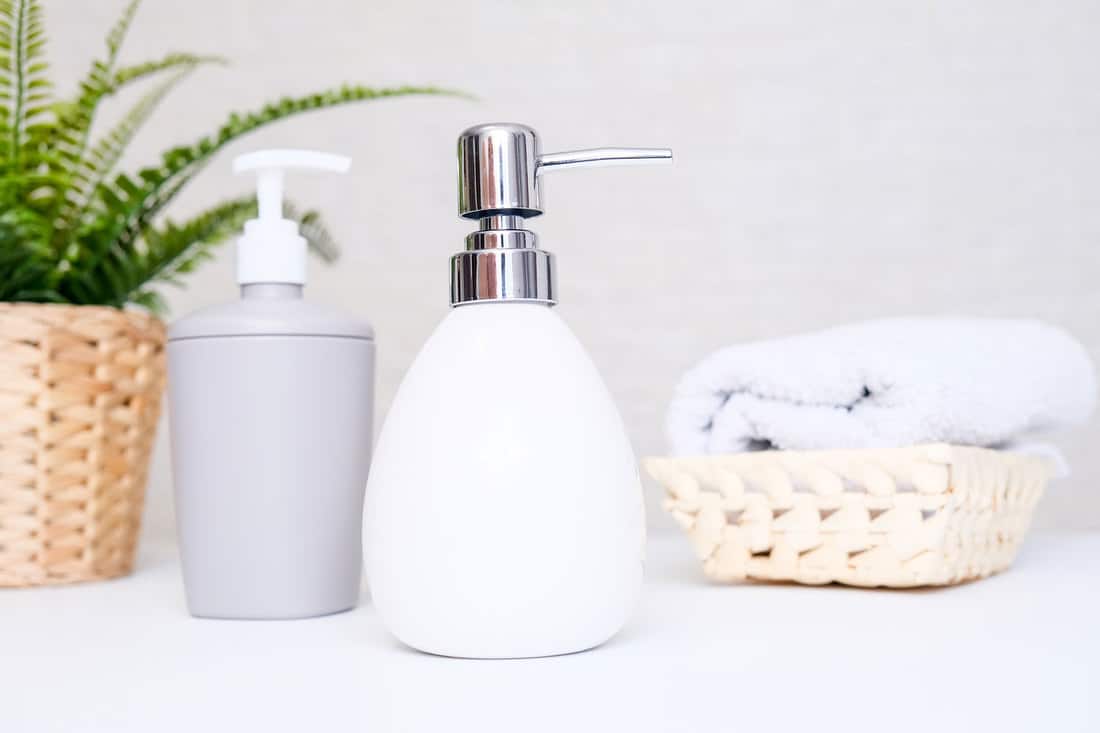 Bathroom background, toilet accessories for hand and body care, liquid soap dispenser and towels against light background, 9 Types Of Soap Dispensers