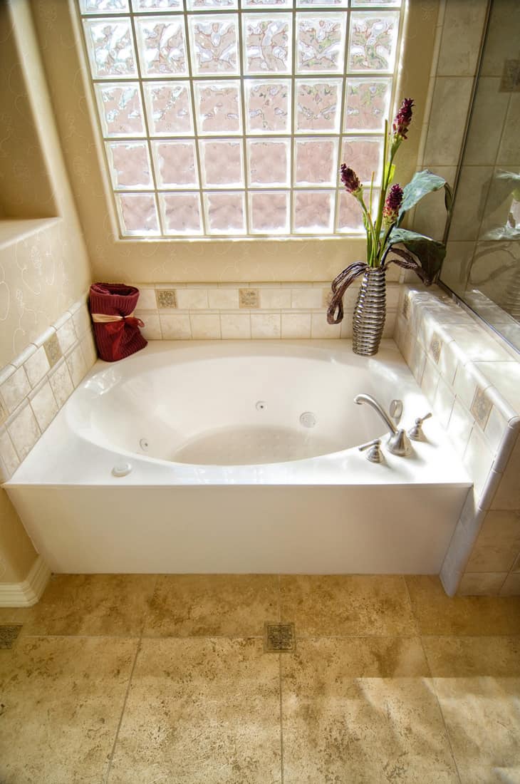 Salle de bain avec baignoire et mur de briques de verre