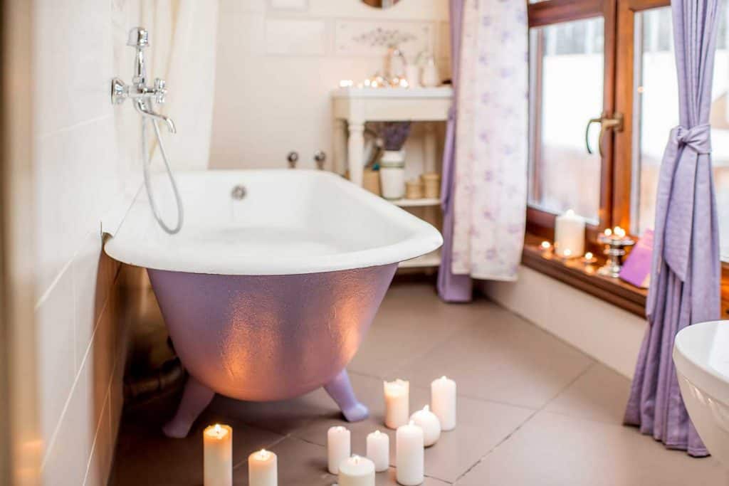 Bel intérieur de salle de bain avec baignoire violette rétro décorée de bougies