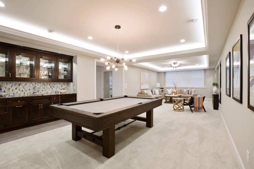 Billiards table with kitchenette nearby in the basement