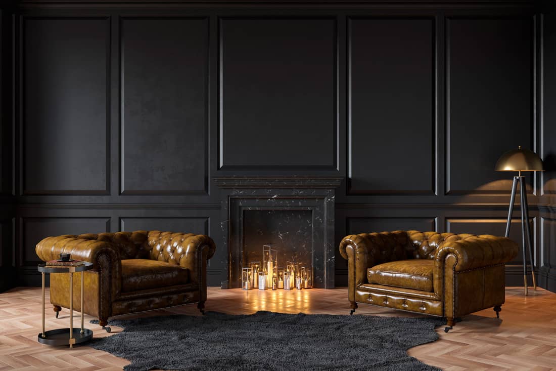 Black classic interior with fireplace, leather armchairs, carpet, candles.