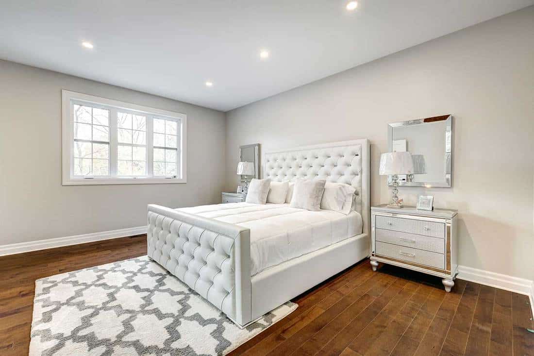 Brand new furnished modern house bedroom with white bed and hardwood floors