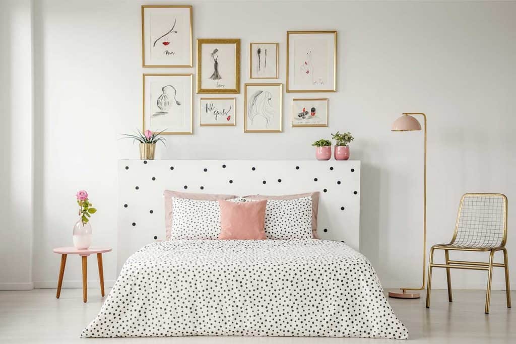 Bright bedroom interior with dotted sheets, headrest, double bed, gold accents and art gallery above