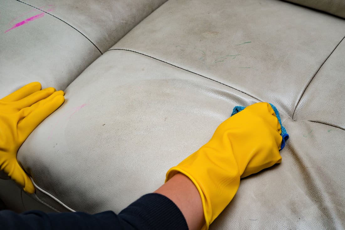 Cleaning leather sofa at home with wet towel