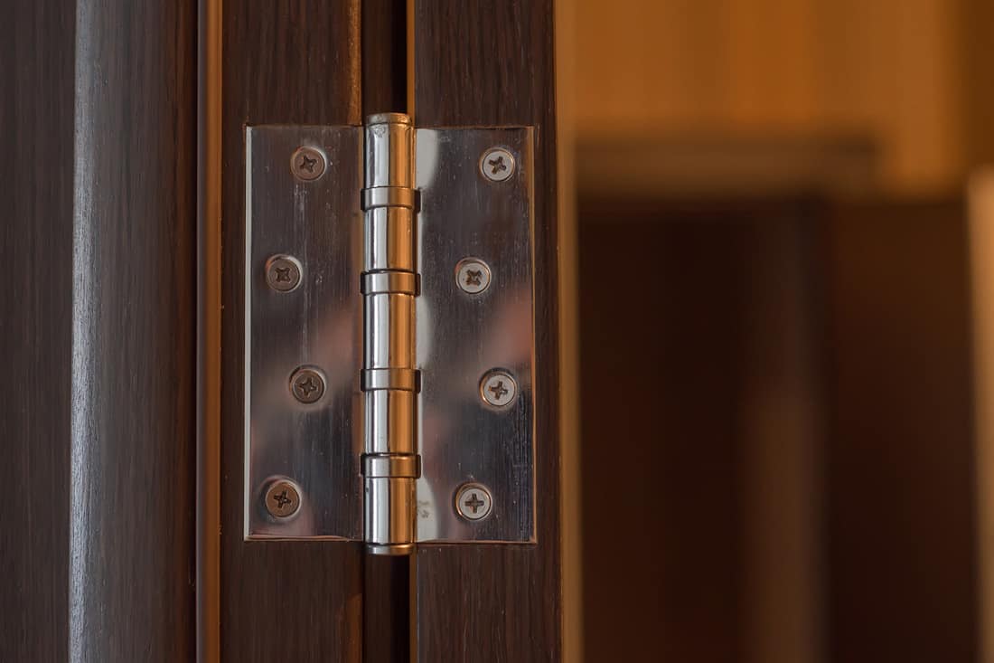 Close-up new modern door hinge on wooden door.