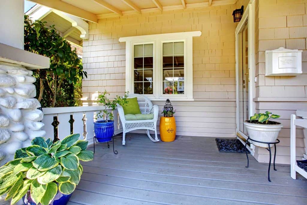 Covered entrance porch with plants and chair