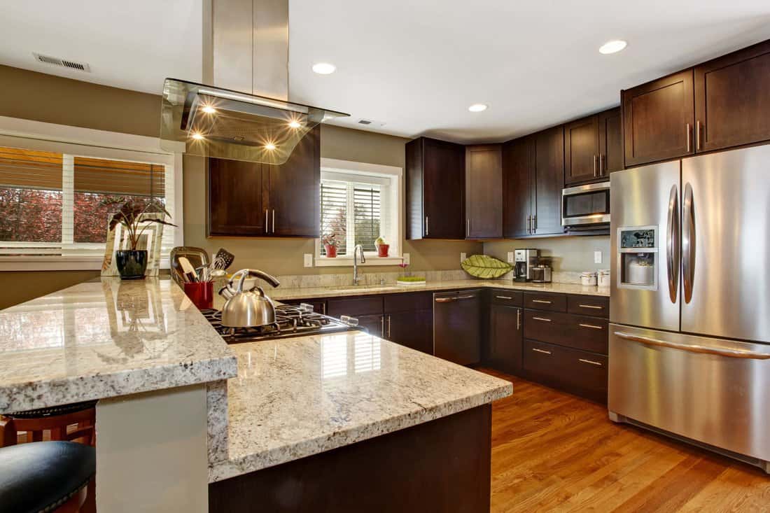 Dark brown kitchen room with steel appliances and hardwood floor 