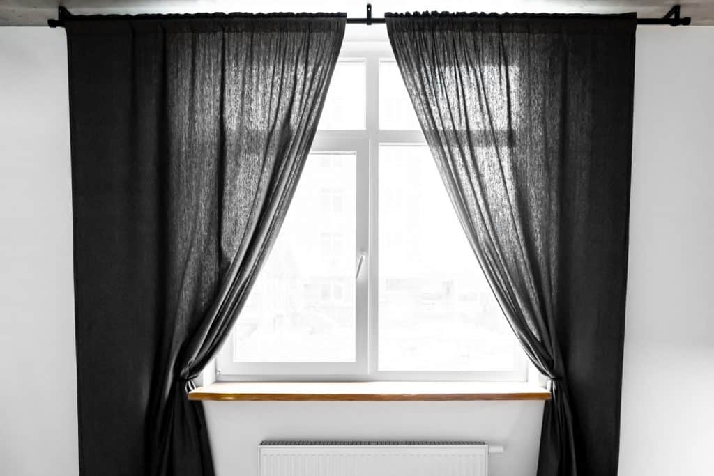 Rideaux sombres à plis pincés sur une fenêtre