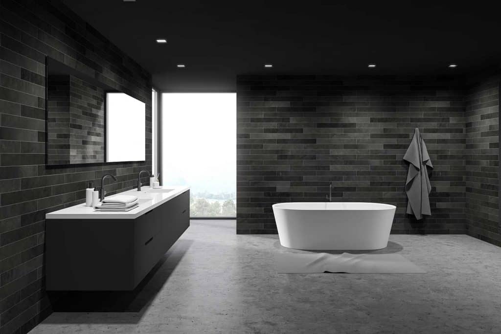 Dark tile spacious bathroom interior, tub and sink