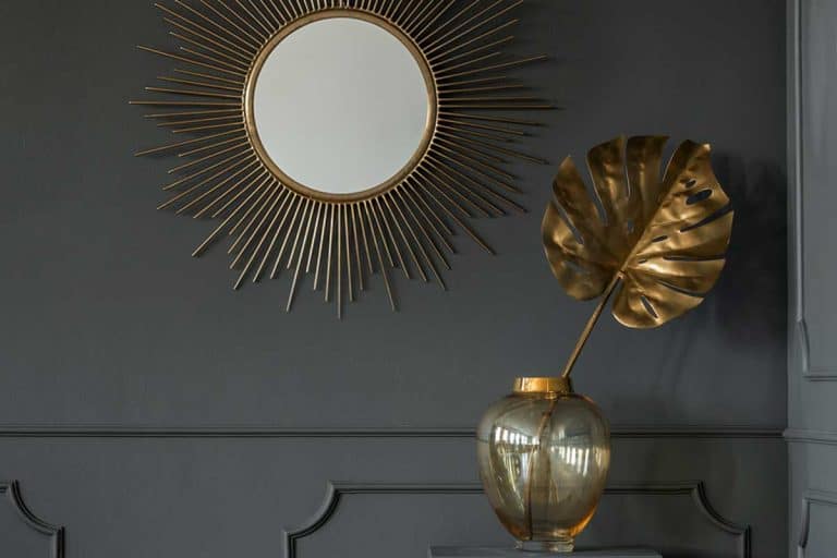 Decorative mirror above a golden plant leaf in a dark luxurious apartment interior, 11 "Wow Factor" Wall Mirror Ideas