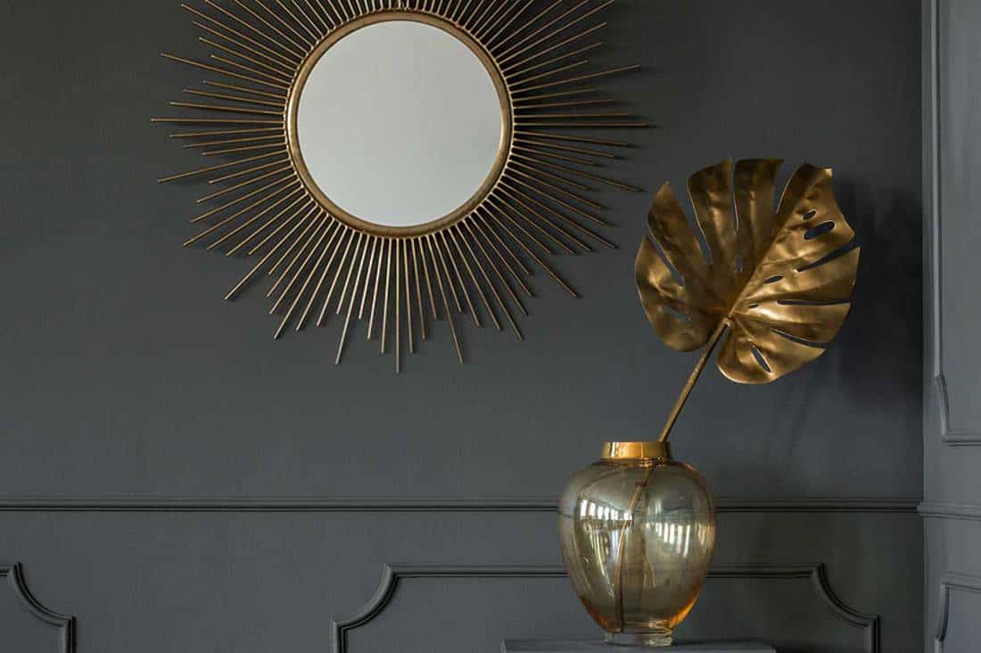Decorative mirror above a golden plant leaf in a dark luxurious apartment interior, 11 