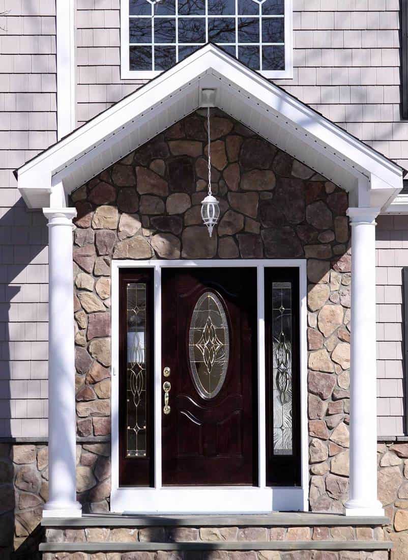 Doorway to home with two white columns and stone front