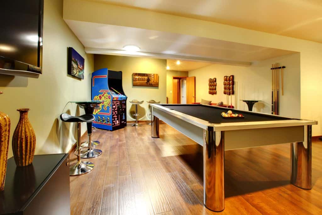 Entertainment area inside a light cream painted basement with hardwood plank flooring