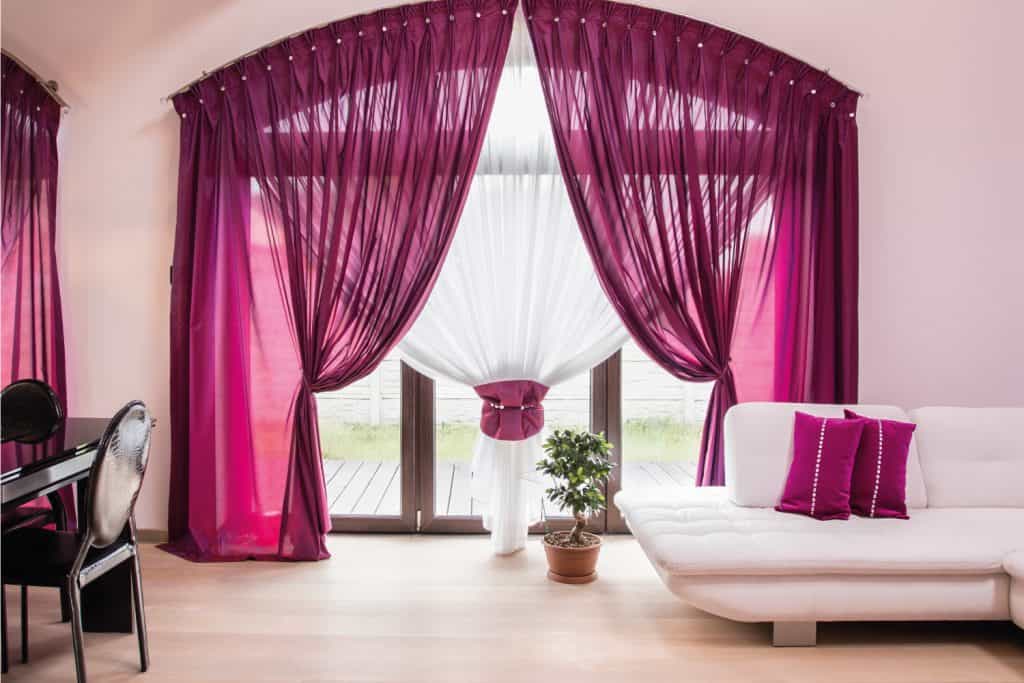 Exaggerated elegant drapes and curtain on a large living room window