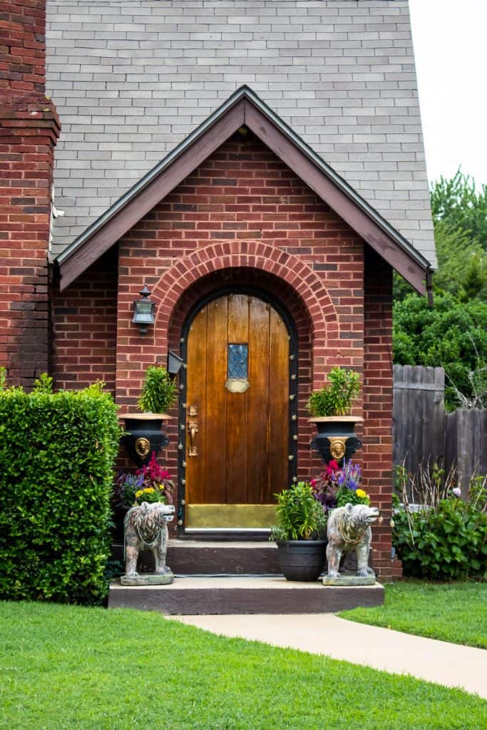 Exterior of a brick house with decorative lions on the front porch and hedges for landscaping