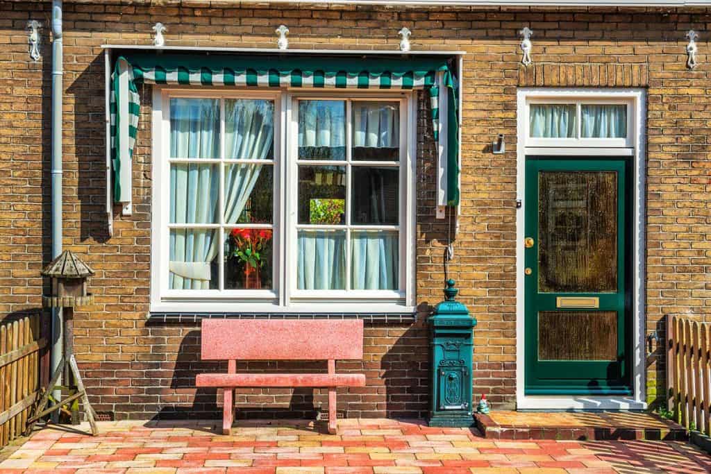 Front porch of house with wooden door and bench