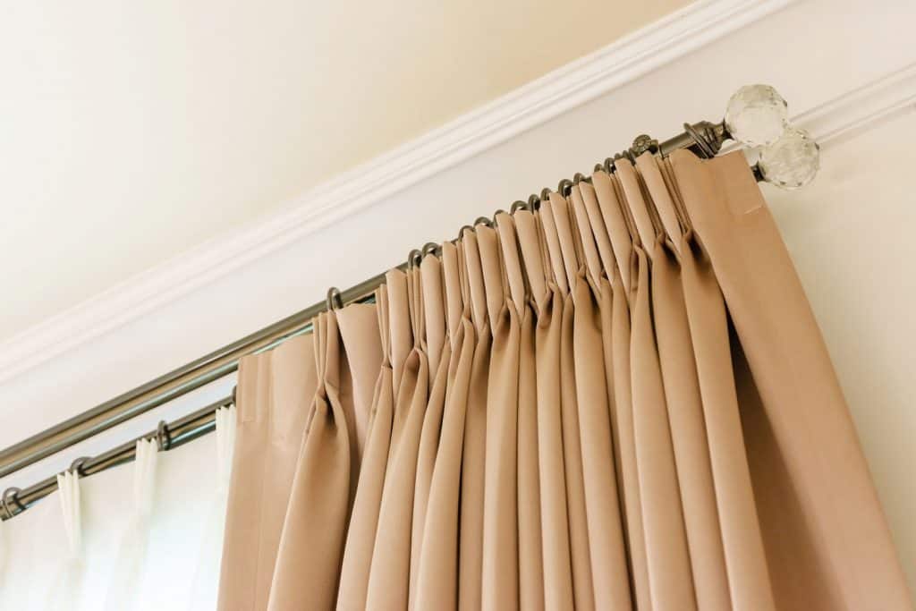 De magnifiques rideaux à plis pincés marron à l'intérieur d'un salon à mur blanc