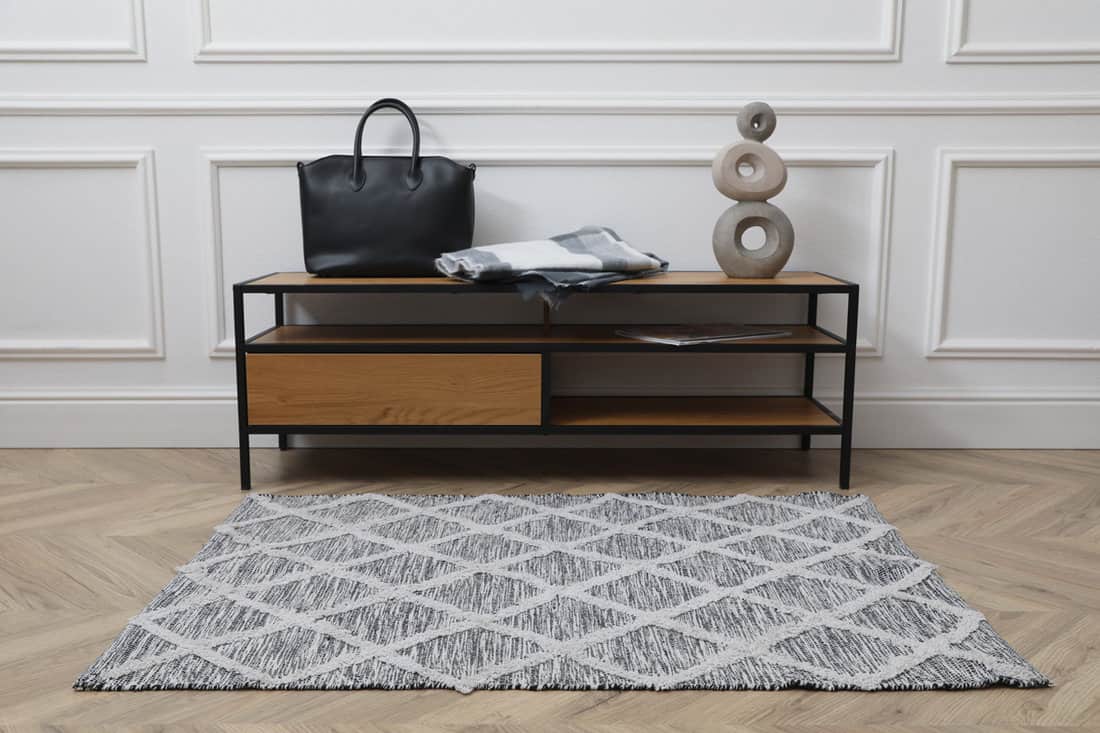 Grey pattern rug inside a white walled living room and light hardwood flooring