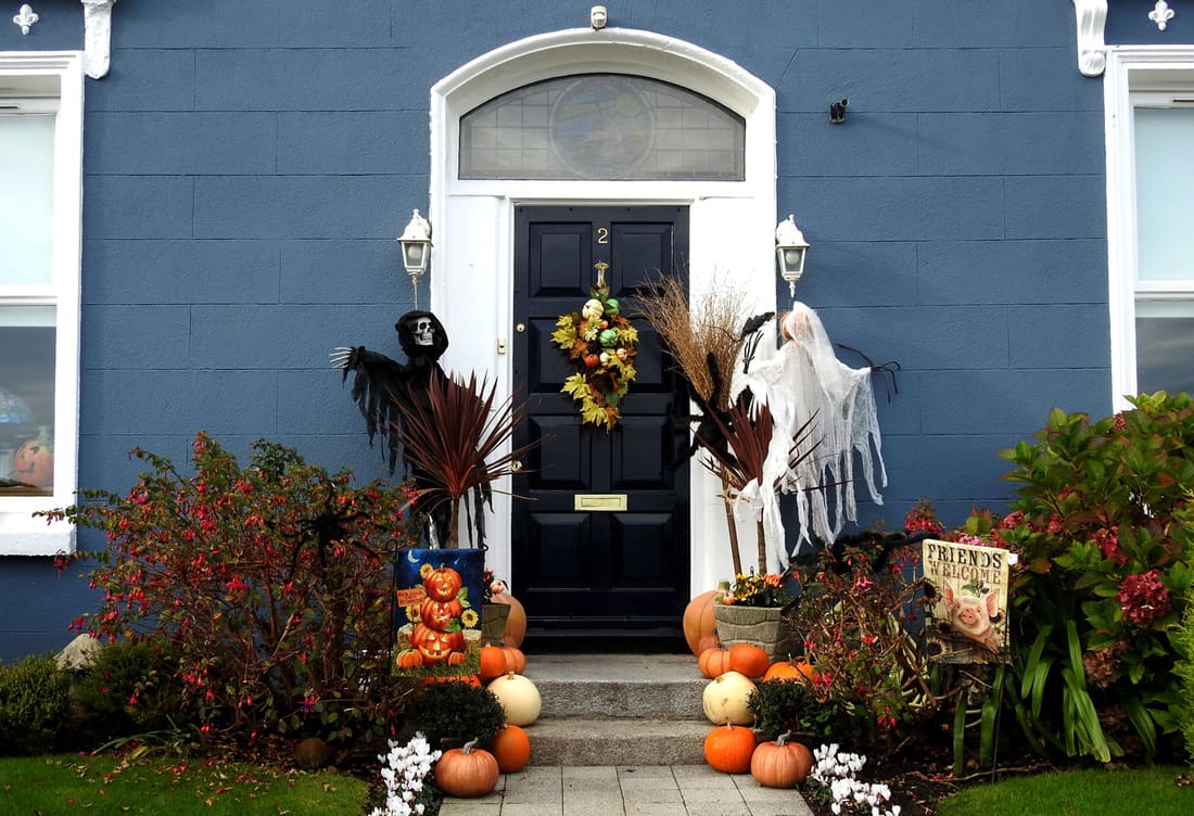 Halloween display of ghosts and pumpkins outside a house 