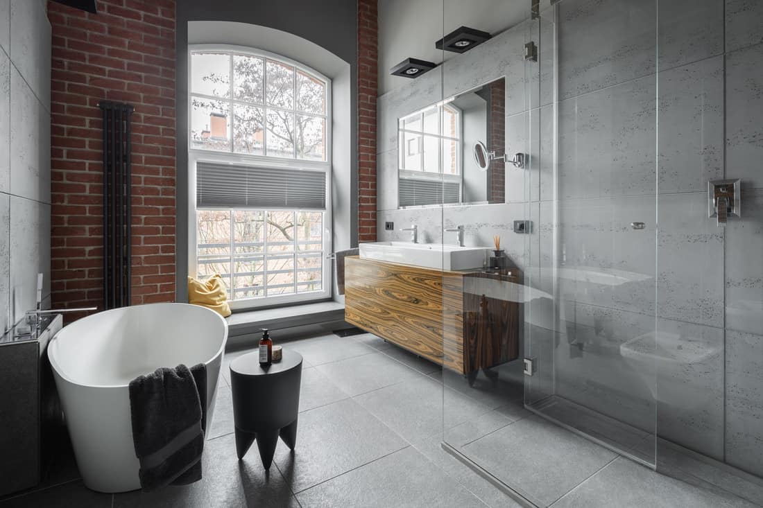 Industrial style bathroom with oval bathtub and walk in shower and brick wall covering