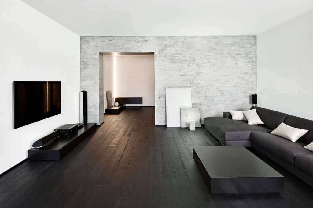 Interior of a black and white themed living room with white painted walls and a wall mounted tv