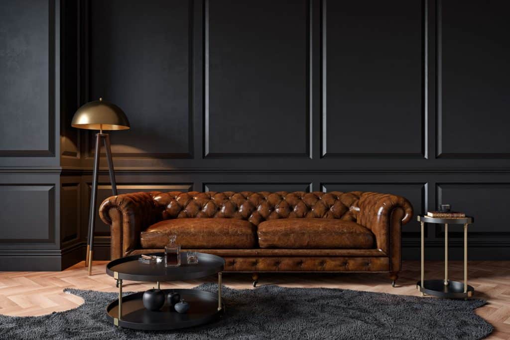 Interior of a dark living room with black colored flat paneled wall and a dark leather sofa