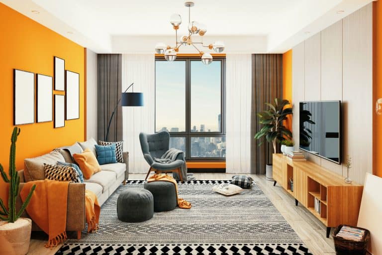 Interior of a luxurious modern contemporary living room with bright orange colored walls, drapes, and throw pillows, 11 Practical Living Rooms With No Coffee Table