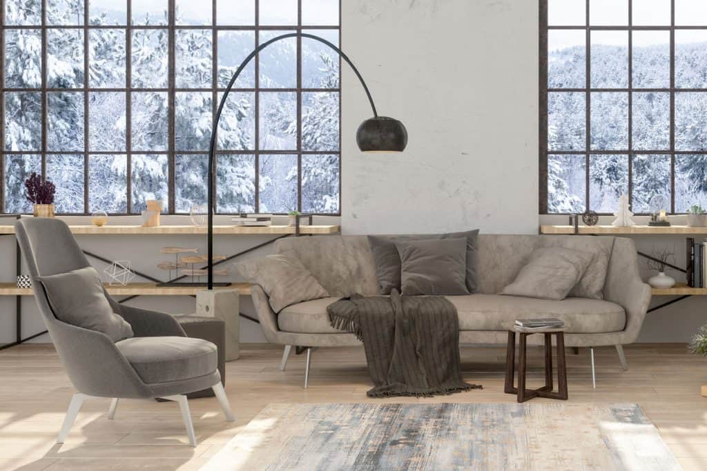 Interior of an industrial themed living room with light wooden cabinet and light gray sofas and chairs