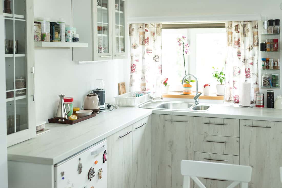 Interior of modern white wooden kitchen with kitchen window curtain, How Long Should Kitchen Window Curtains Be?