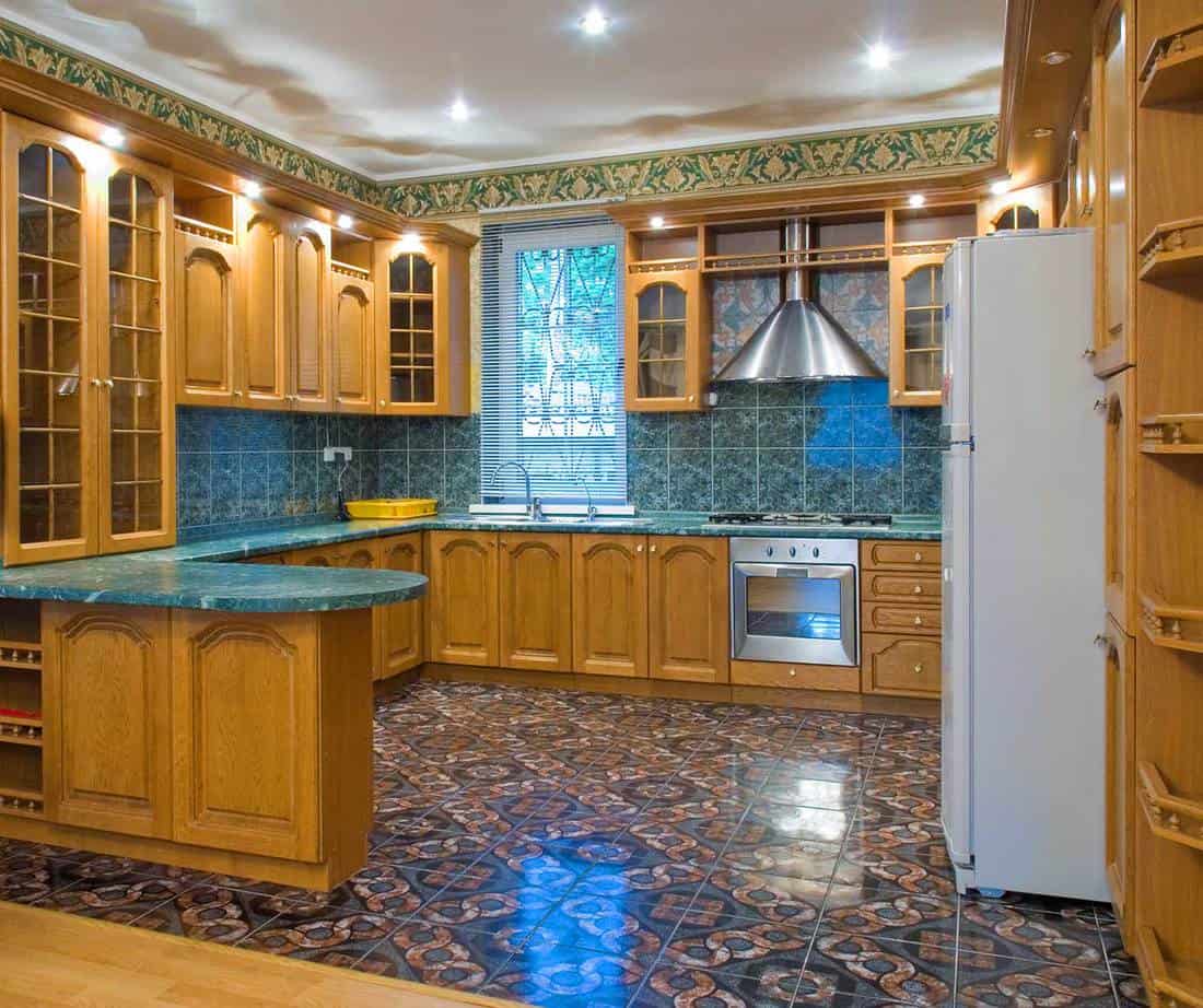 Kitchen interior with wooden cabinets, blue countertop and tiled floor