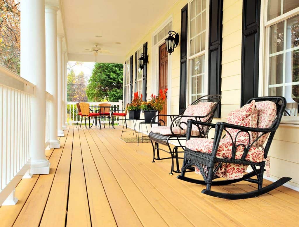Large front porch with furniture and potted plants