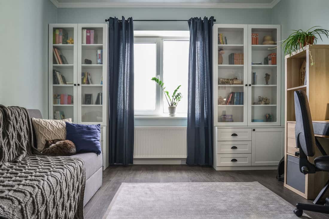 Chambre d'adolescent confortable et lumineuse avec des bibliothèques blanches, un canapé gris et des murs bleus, quelle devrait être la longueur du rideau pour des plafonds de 12 pieds ?