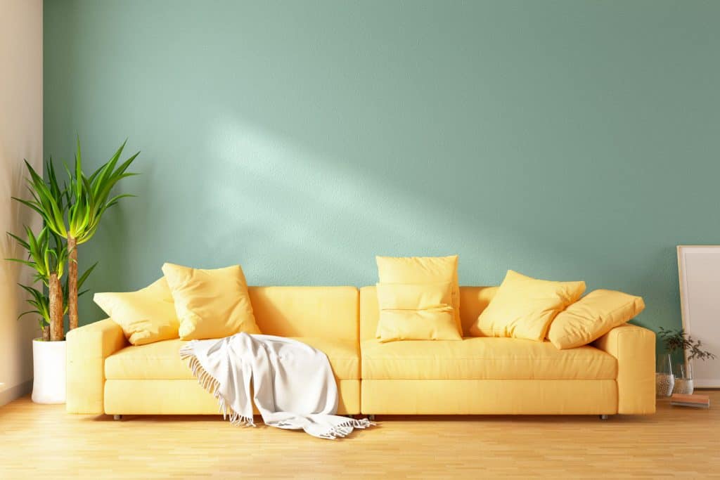 Living room with a green wall, yellow long sofa, and an indoor plant