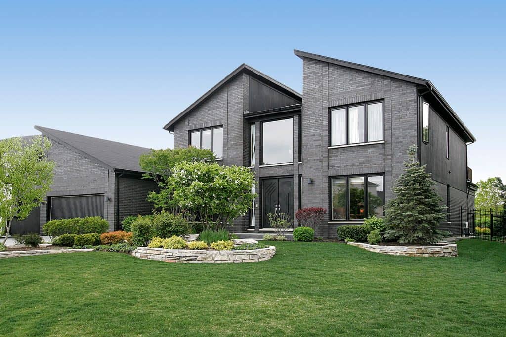 Luxurious contemporary mansion with huge picture windows, wedged roofing, gray decorative sidings, and a gorgeous front lawn landscaping, 17 Eye-Catching Grey House Ideas